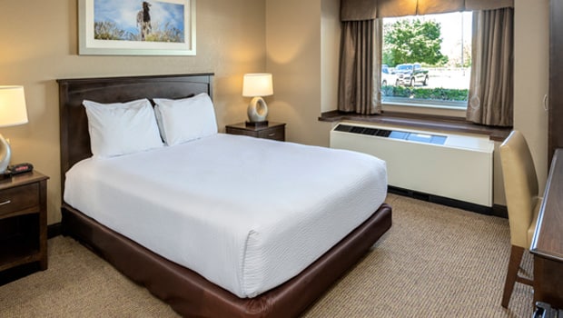 a queen size bed with white linens in a hotel room