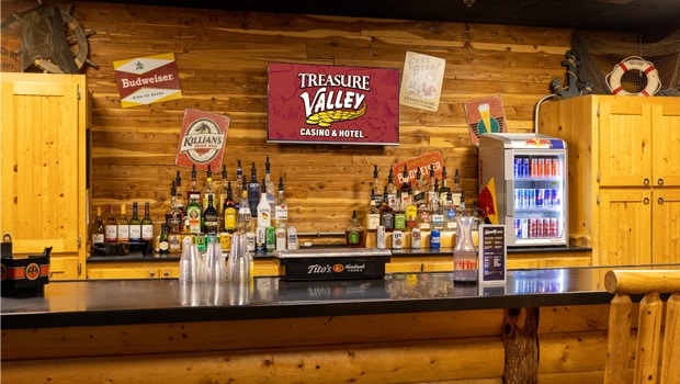 a bar with wood walls and stocked with various liquors and beverages