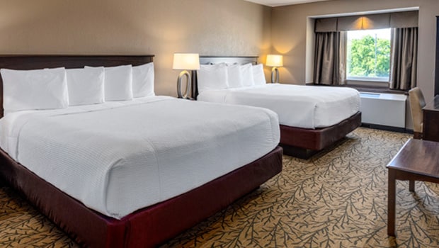 two king size beds with white linens in a hotel room