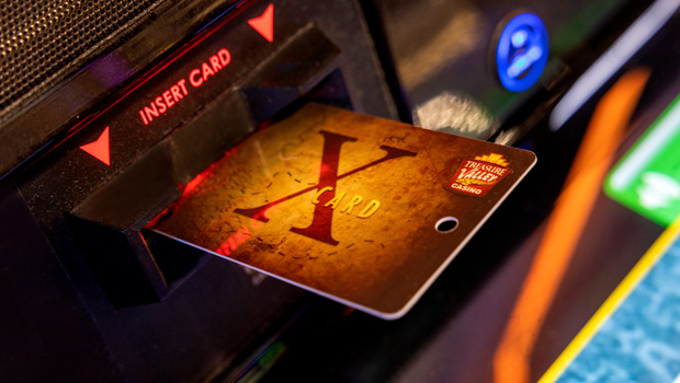gold x card sticking out of a slot machine